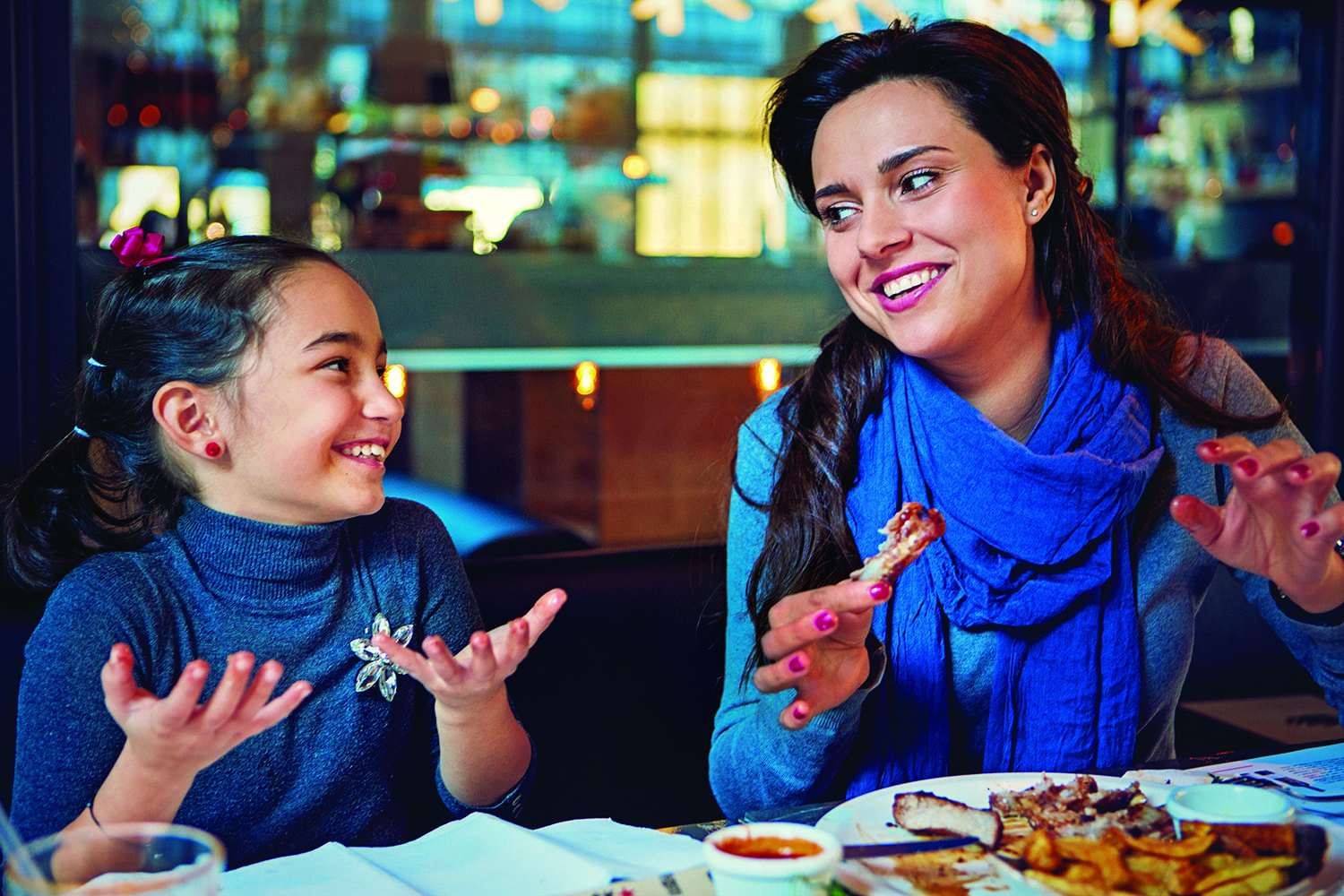Mother and daughter enjoying a meal and conversation at a restaurant.