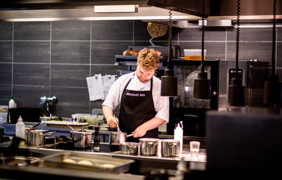 Chef cooking in a professional kitchen with stainless steel equipment