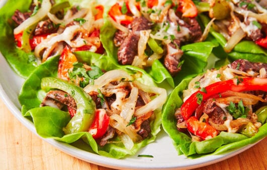 Beef fajitas on lettuce wraps with grilled vegetables on a plate